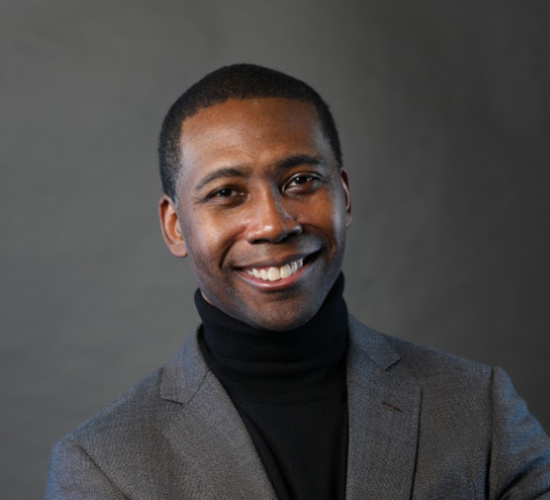 Dr. Rollo Dilworth similing in a black turtleneck and grey blazer