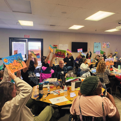 A group of adults holding their artwork in the air to show others